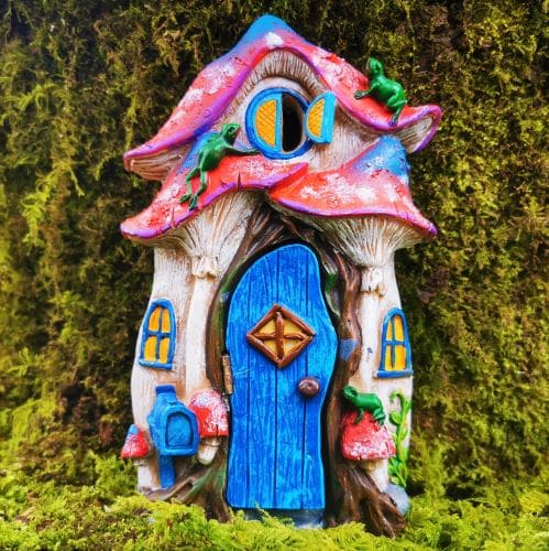 the frog cottage opening fairy door against a tree